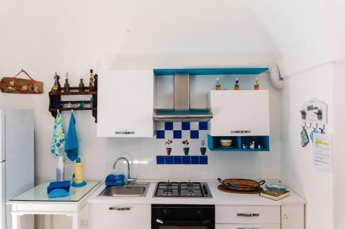 a small kitchen with white cabinets and blue tiles at Iolanda Vacanze in Lucugnano