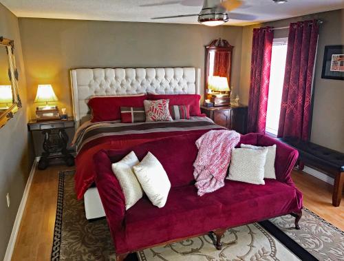 ナイアガラ・オン・ザ・レイクにあるButler Creek Houseのベッドルーム(大型ベッド1台、赤いソファ付)