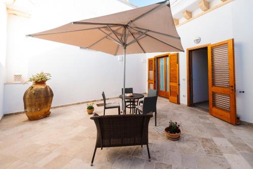 a patio with an umbrella and a table and chairs at Iolanda Vacanze in Lucugnano