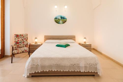 a white bedroom with a bed and a chair at Iolanda Vacanze in Lucugnano