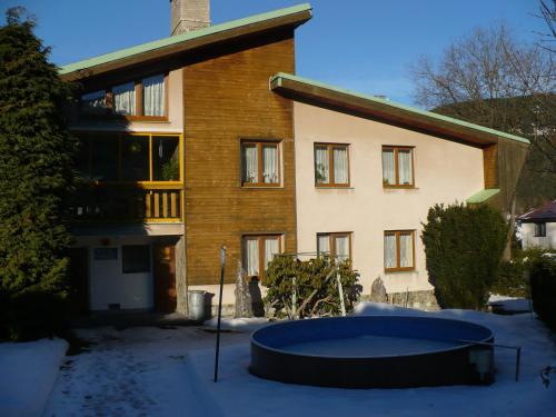 a house with a tub in front of it in the snow at Ubytování Zmatlíková in Pec pod Sněžkou