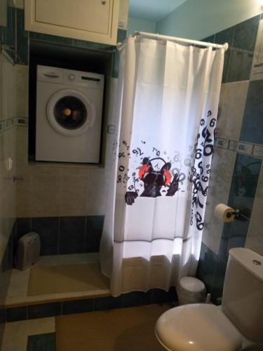 a bathroom with a washing machine and a shower curtain at Home Spot Nafplio in Nafplio
