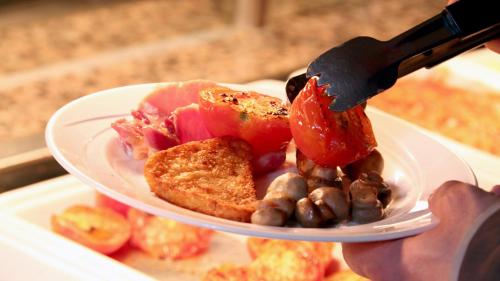 a person holding a knife and a plate of food at Holiday Inn Maidstone-Sevenoaks by IHG in Maidstone