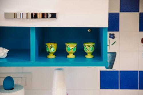 a blue shelf with three gold cups on it at Iolanda Vacanze in Lucugnano