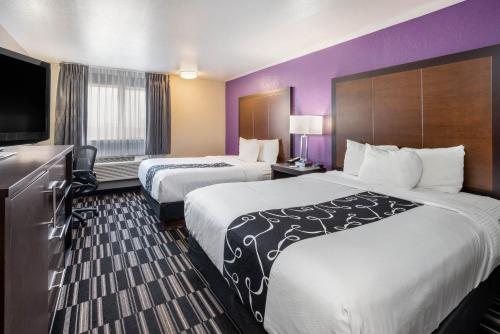 a hotel room with two beds and a flat screen tv at La Quinta Inn by Wyndham Caldwell in Caldwell