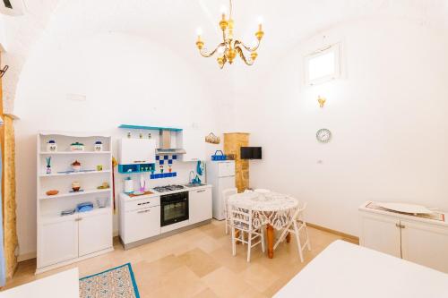 a kitchen with white cabinets and a table and a chandelier at Iolanda Vacanze in Lucugnano
