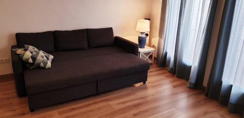 um sofá preto numa sala de estar com um candeeiro em Apartamento acogedor a 3 minutos de la playa em Blanes