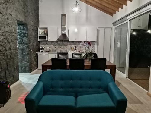 a living room with a blue couch and a kitchen at GRANARY'S HOUSE in Sete Cidades