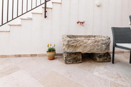 a stone bowl sitting on a patio with a chair at Iolanda Vacanze in Lucugnano