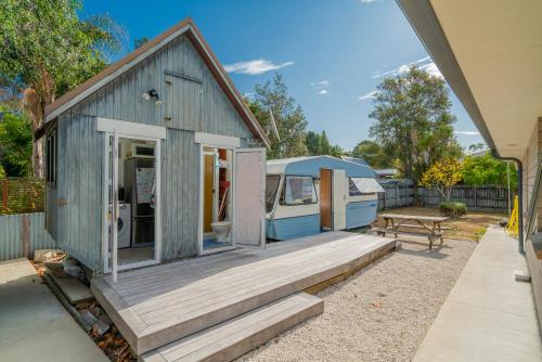 una piccola casa blu con un portico e un tavolo da picnic di Rose's Beach Pad - Matarangi Holiday Home a Matarangi