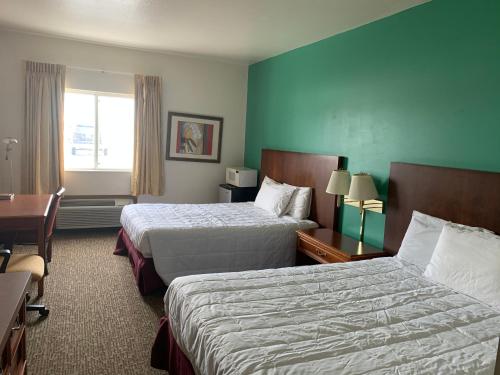 a hotel room with two beds and a desk at Americas Best Value Inn - Gaylord in Gaylord