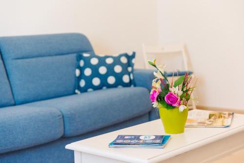 a living room with a blue couch and a table with flowers at Iolanda Vacanze in Lucugnano