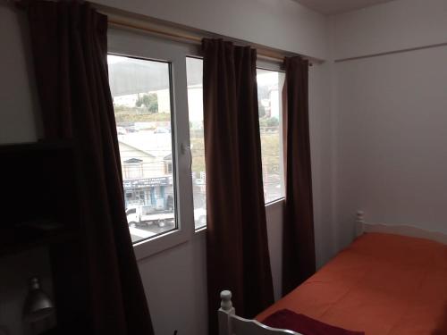 1 dormitorio con 2 ventanas y 1 cama. en Seliuqanan en Ushuaia