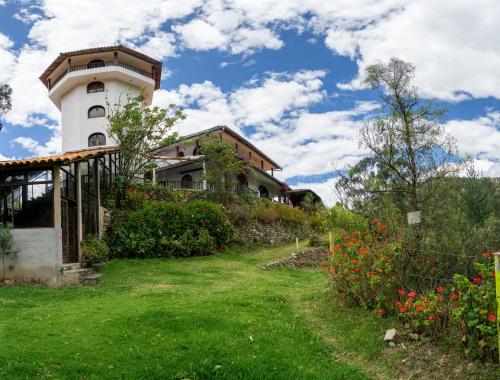 a house with a tower on top of a green yard at Fundo El Chocho in Cajamarca