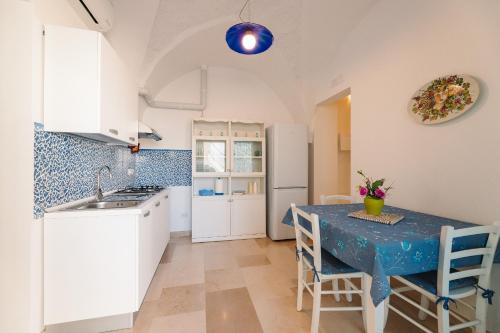 a kitchen with a table with chairs and a sink at Iolanda Vacanze in Lucugnano