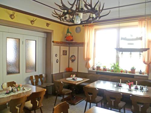 a restaurant with tables and chairs and a chandelier at Fränkischer Hof in Mainleus