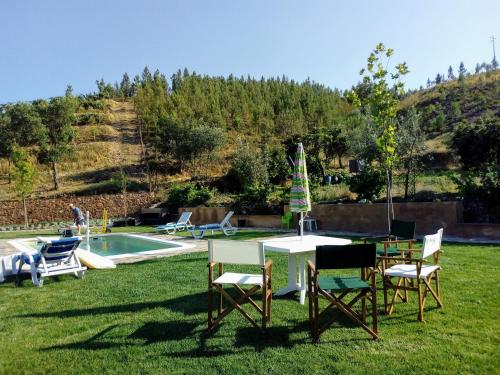 a yard with chairs and a table and a pool at REFÚGIO DO RAPOSO/CASA DENEB (CC) in Montes da Senhora