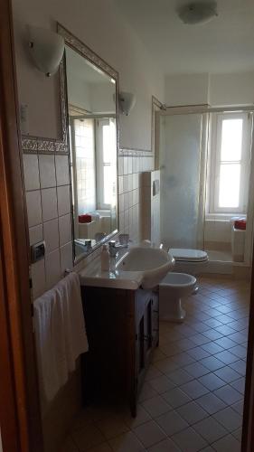 een badkamer met een wastafel, een toilet en een spiegel bij Pisicchio Rooms in Fiumicino