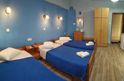 een kamer met 3 bedden en blauwe muren bij Prosforio in Ouranoupoli