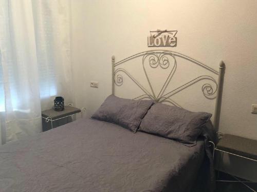 a bedroom with a bed with a love sign above it at Apartamento en La Almadraba in Chiclana de la Frontera