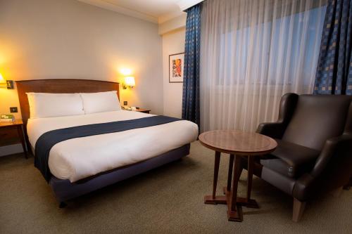 a hotel room with a bed and a chair at Best Western London Heathrow Ariel Hotel in Hillingdon