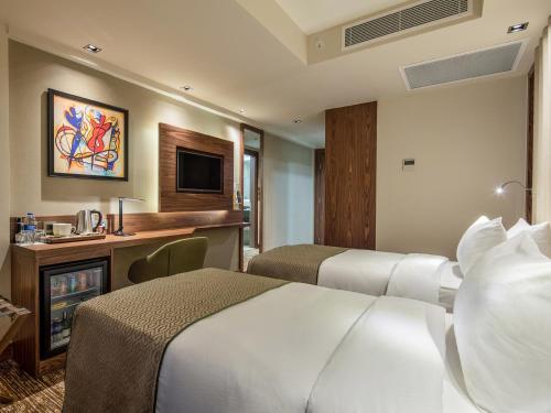 a hotel room with two beds and a television at Holiday Inn Antalya - Lara by IHG in Antalya