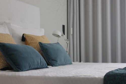 uma cama com almofadas azuis em cima em Duque de Loulé - Apartments - Apartamento D em São Martinho do Porto