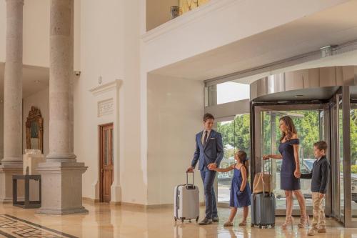 a man and a woman and two children with luggage at Presidente InterContinental Puebla by IHG in Puebla