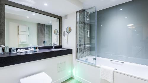 a bathroom with a shower and a sink and a mirror at Holiday Inn Slough Windsor, an IHG Hotel in Slough