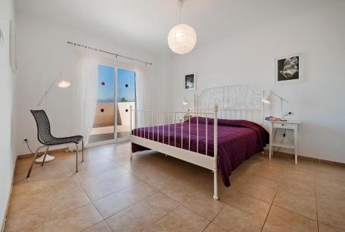 um quarto com uma cama roxa e uma cadeira em Villa Marisa I em Alcudia