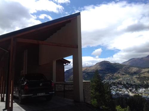 un coche aparcado en un edificio con montañas al fondo en Altos de Esquel en Esquel