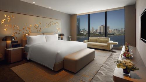 a bedroom with a large white bed and a living room at InterContinental Tianjin Yujiapu Hotel & Residences by IHG in Binhai