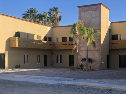 a building with a palm tree in front of it at Sea Rock Hotel in Puerto Peñasco