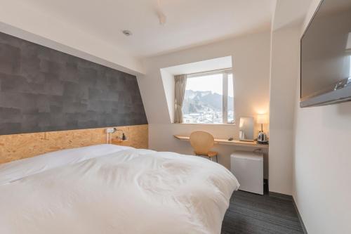 1 dormitorio con cama, escritorio y ventana en Nikko Station Hotel 2 en Nikko