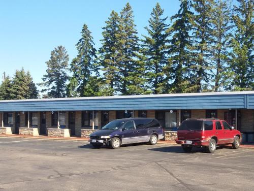 dos autos estacionados en un estacionamiento frente a un edificio en Hotel Blue Top Inn, en Stevens Point