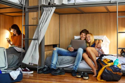 two women sitting on a bed with a laptop at Franca City Hostel in Buenos Aires