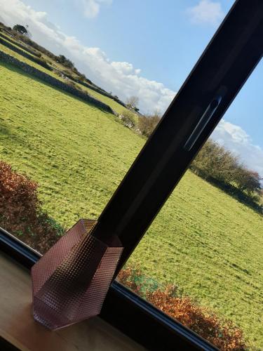 a chair sitting in a window looking out at a field at Cong Getaway Lodge in Mayo