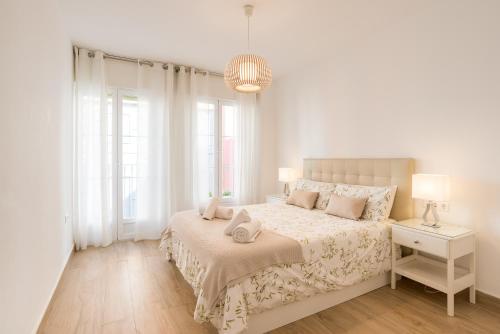 a white bedroom with a large bed and a lamp at Agua III & balconies by ELE Apartments in Málaga