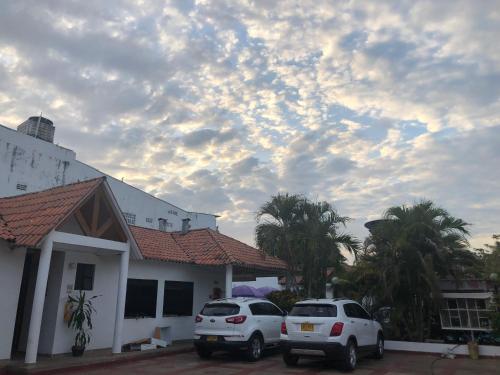 two cars parked in a parking lot in front of a house at Hotel Villa Ricaurte in Girardot