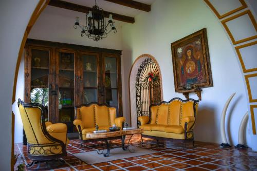 a living room with yellow chairs and a table at Hotel Hacienda San Isidro in San Isidro Mazatepec