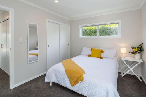 a white bedroom with a bed and two windows at Easy Days Martinborough in Martinborough 