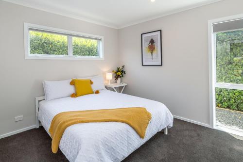 a white bedroom with a bed and two windows at Easy Days Martinborough in Martinborough 