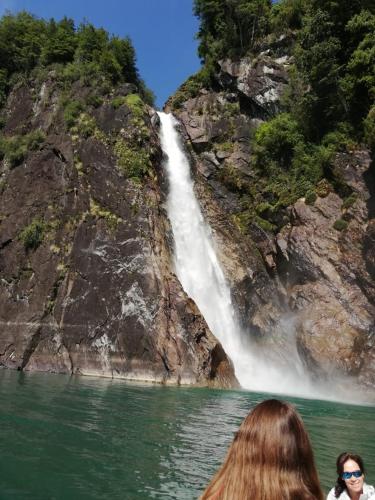 two people in a boat in front of a waterfall at Cabañas Nutrias Patagonicas in Puelo