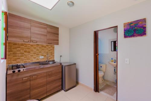 a kitchen with wooden cabinets and a sink and a toilet at Hostal Doña Eliza in Bogotá