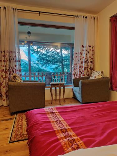 a living room with a bed and a large window at Kudrat - A Boutique Homestay- Tirthan Valley in Banjār