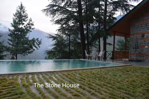 a house with a swimming pool with mountains in the background at Kudrat - A Boutique Homestay- Tirthan Valley in Banjār