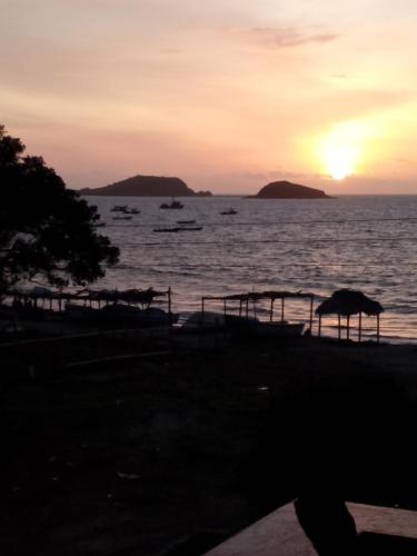 una puesta de sol sobre el agua con islas en la distancia en Hospedaje Algarrobo Machalilla en Machalilla