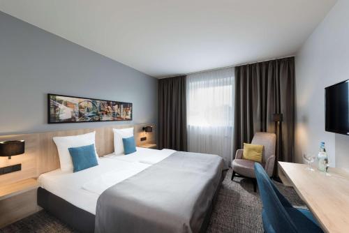 Habitación de hotel con cama grande y escritorio. en Ramada by Wyndham Flensburg, en Flensburg