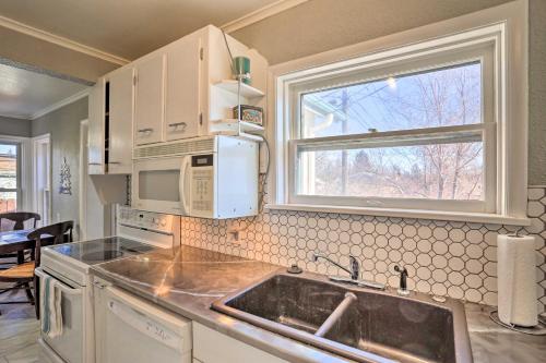 a kitchen with a sink and a microwave and a window at Rapid City Home with Patio by Canyon Lake Park! in Rapid City