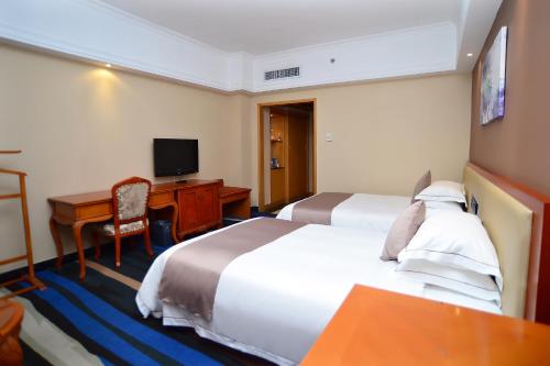 a hotel room with two beds and a desk and a television at Shenzhen Kaili Hotel, Guomao Shopping Mall in Shenzhen